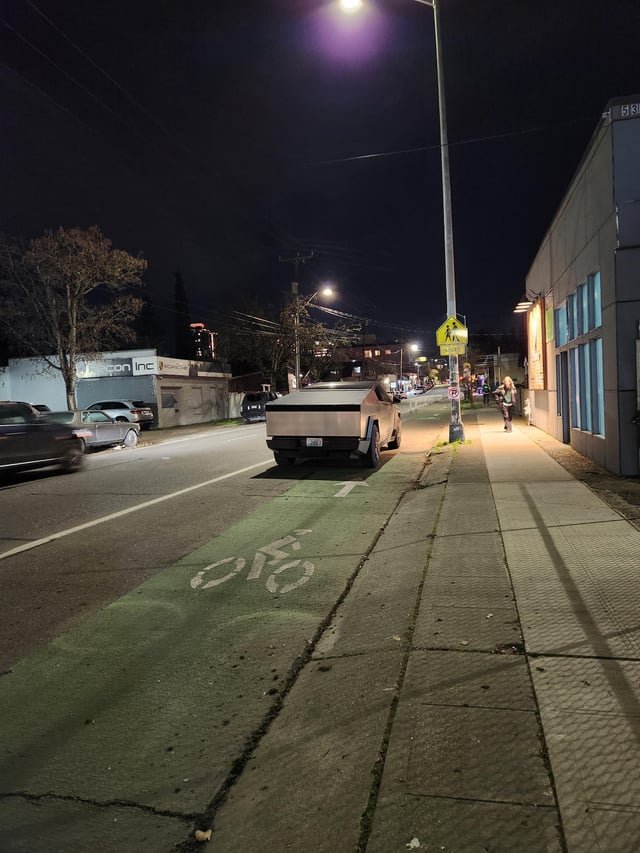 Cyber truck parked right in front of a no parking sign in a bike lane