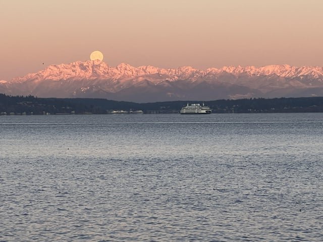 Moon setting over Olympics with sunrise lighting the olympics