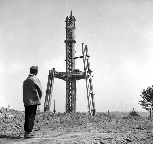 A young boy looks up at the steel frame of the partially completed Space Needle. 1961.