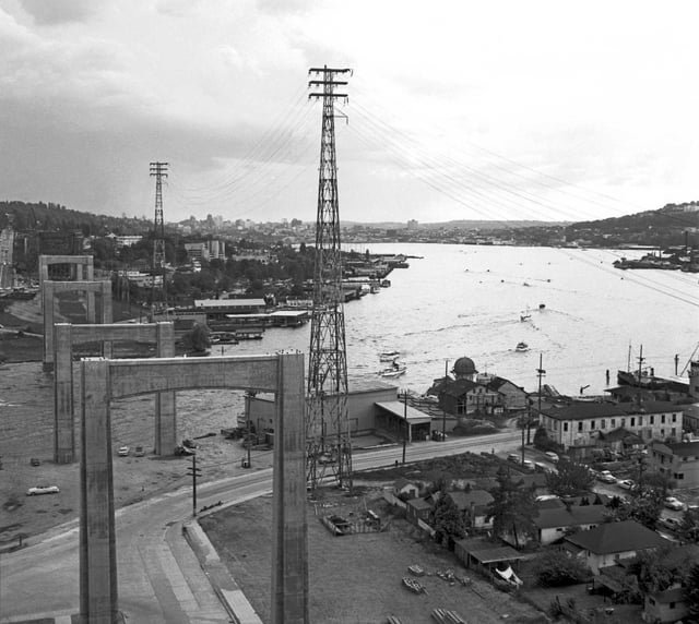 Looking south during construction on the Lake Washington Ship Canal Bridge, summer 1959. Bottom-right are the remnants of the Latona business and industrial district, replaced now with Ivar’s Salmon House and its parking. (Photo by Victor Lygdman)