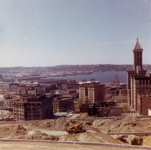 View across I-5 construction towards Smith Tower, Frye Hotel, and Elliot Bay, from roof of 905 Spruce, 1966.