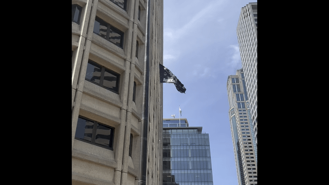 Protesters hoist “Refugees Welcome” flag and non-binary flag to the top of the flagpole at federal building