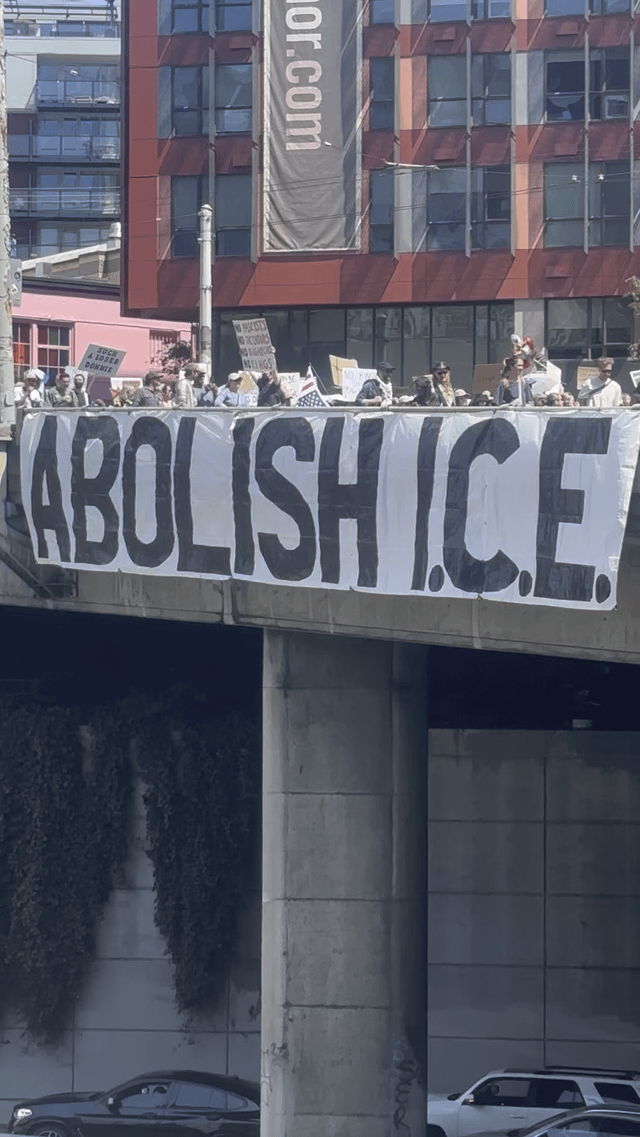 50-foot ABOLISH I.C.E. banner hanging from Pine St. bridge during No Kings March