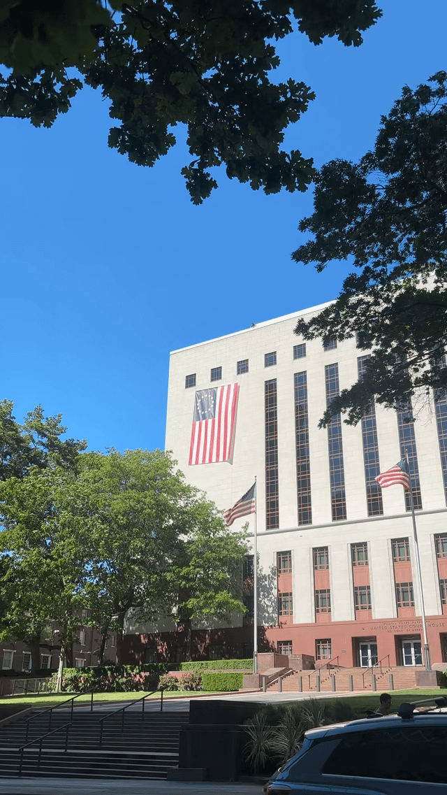 Guy adjusting the Betsy Ross flag hanging off the Federal Courthouse in the crazy wind